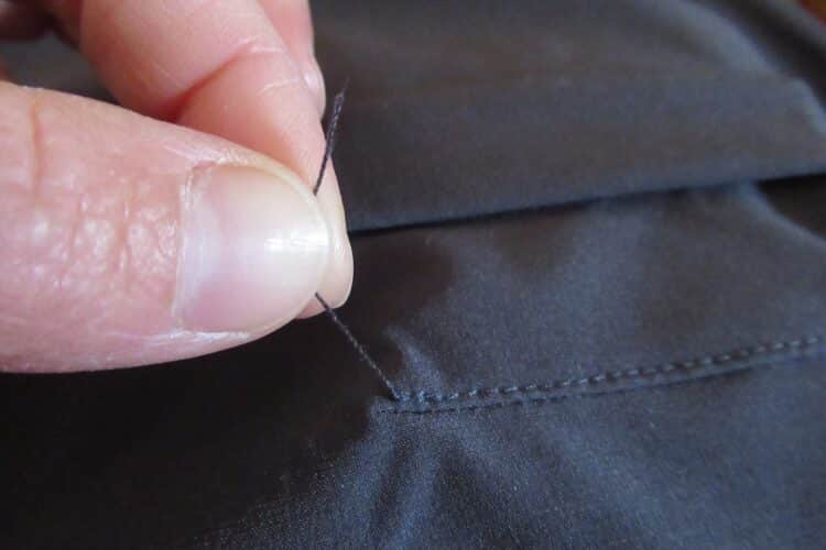 Grand fil qui dépasse sur une couture du pantalon